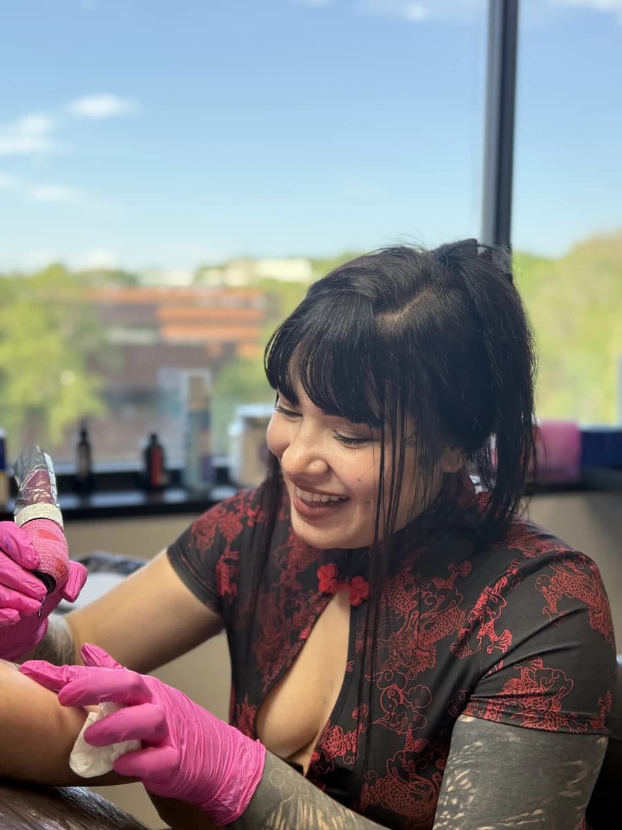 Portrait of Angie, tattoo artist at El Estuche Ink, tattooing a client
